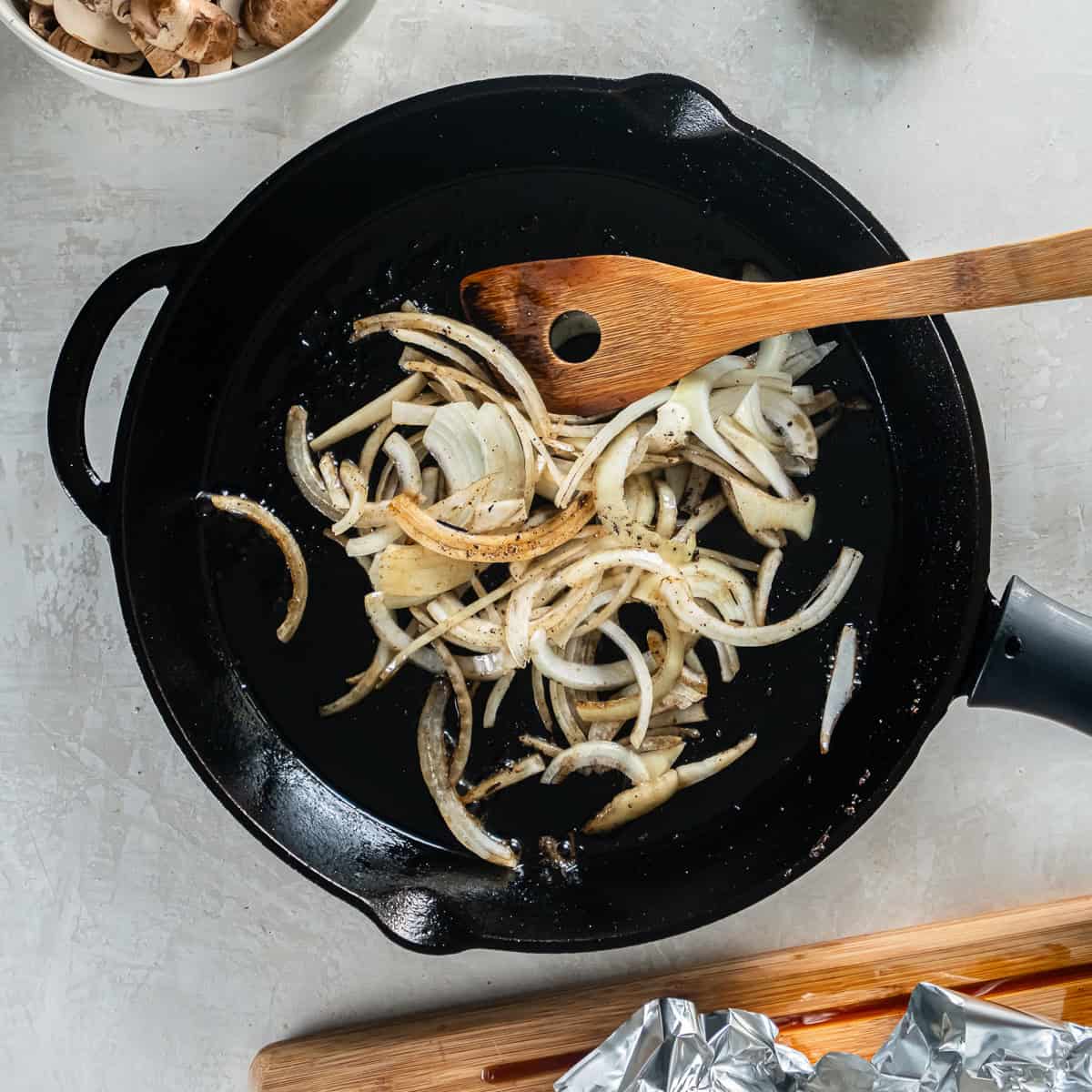 Sliced onions cooking in a cast iron skillet.