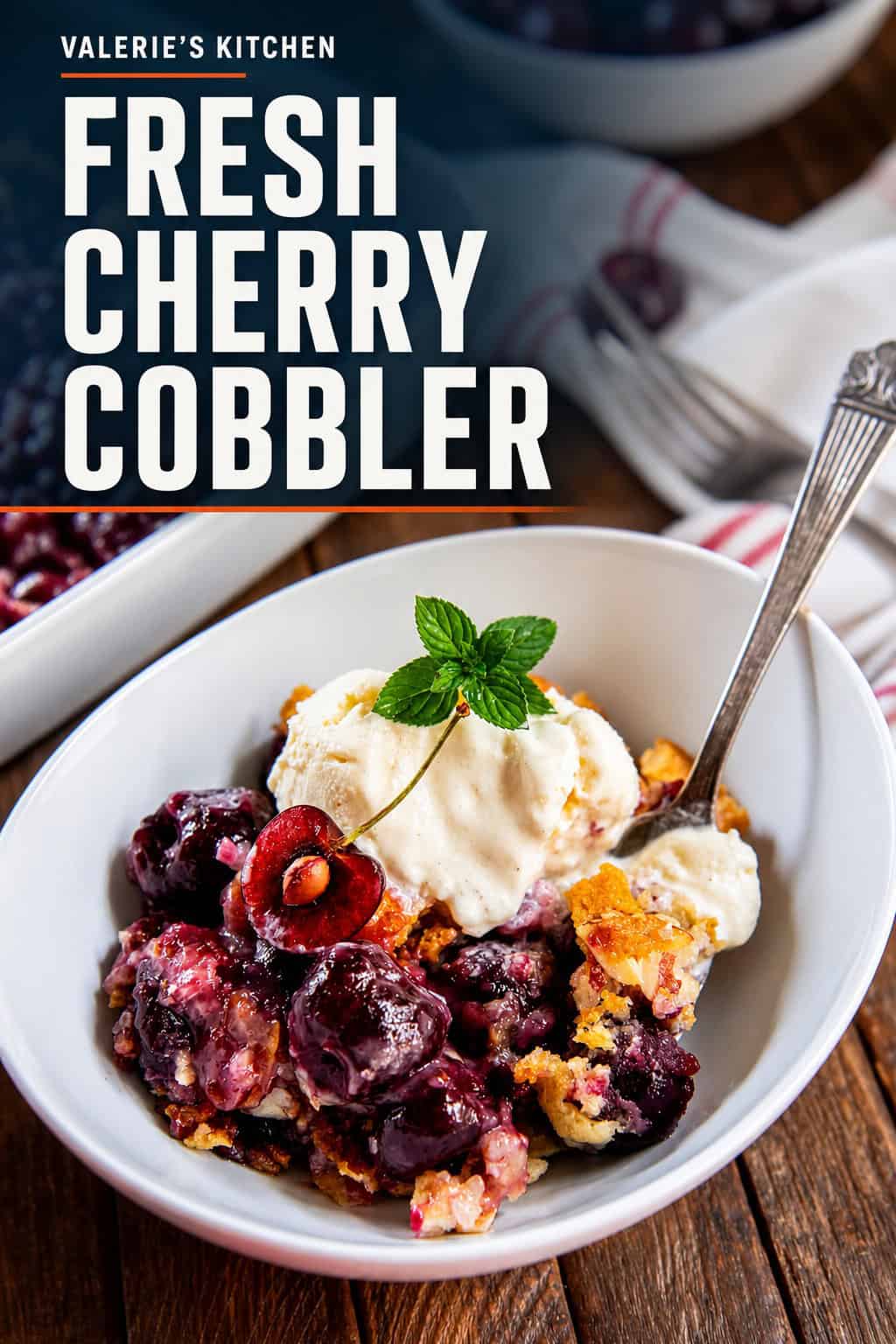 Fresh cherry cobbler topped with vanilla ice cream, a cherry half, and fresh mint in a white bowl with title text overlay.