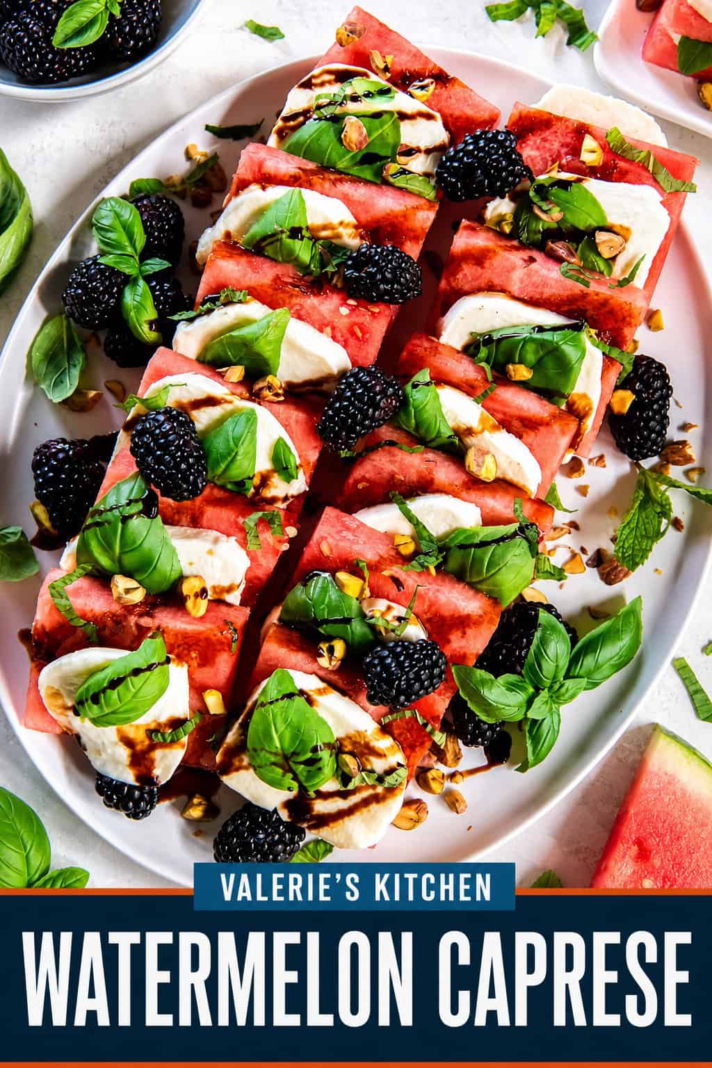 Watermelon Caprese on a serving platter with layers of watermelon, fresh mozzarella, basil leaves, blackberries, chopped pistachios, and balsamic glaze with bold text overlay.
