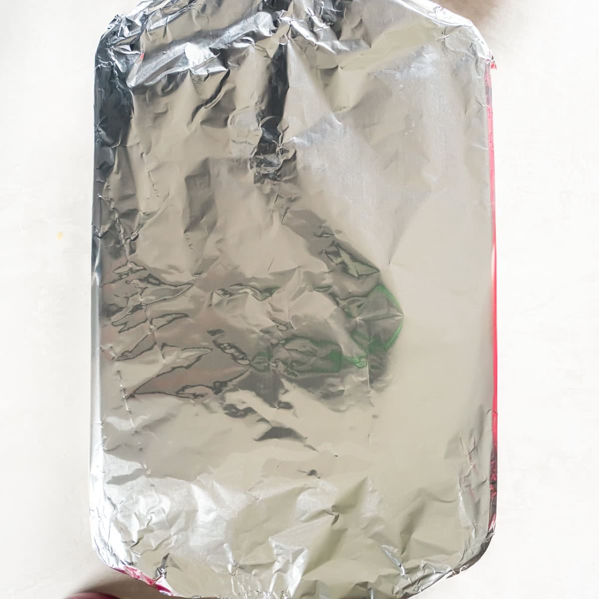 9 slider rolls filled with pulled pork in a baking dish covered tightly with aluminum foil before baking.
