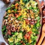 Summer Chicken Salad with bacon, corn, avocado, tomatoes, and Cajun chicken on a bed of fresh greens, served on a wooden platter with apple cider vinaigrette.