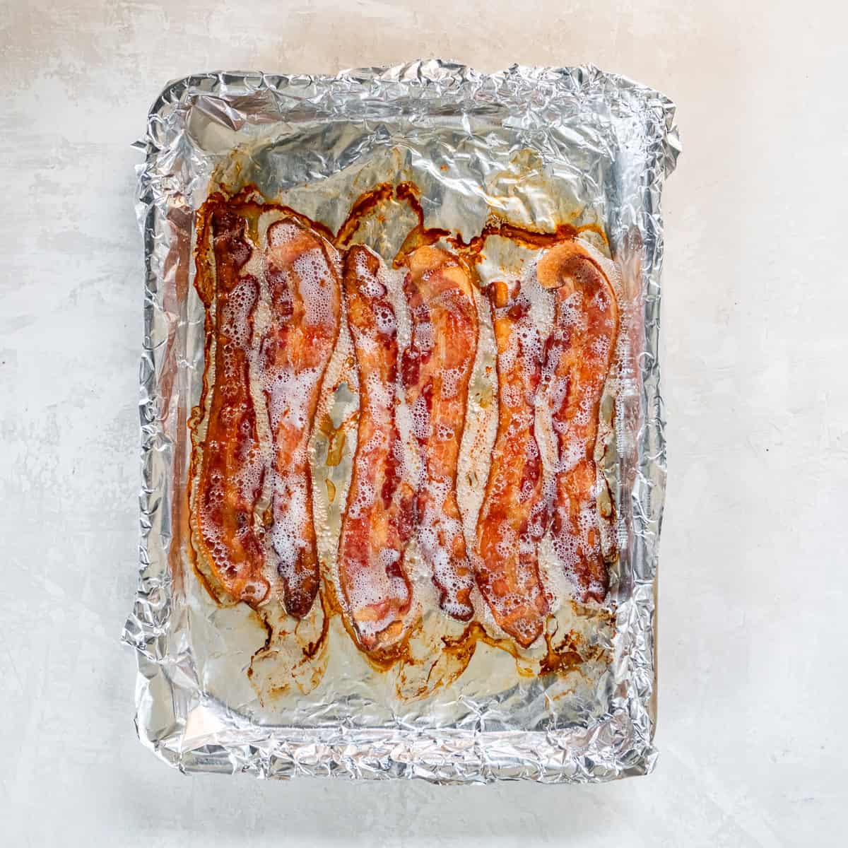 Cooked bacon on a foil-lined baking sheet.