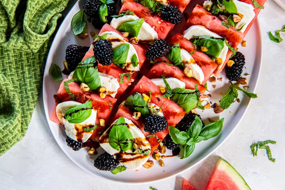 Watermelon Caprese platter with fresh mozzarella, basil, blackberries, pistachios, and balsamic glaze.