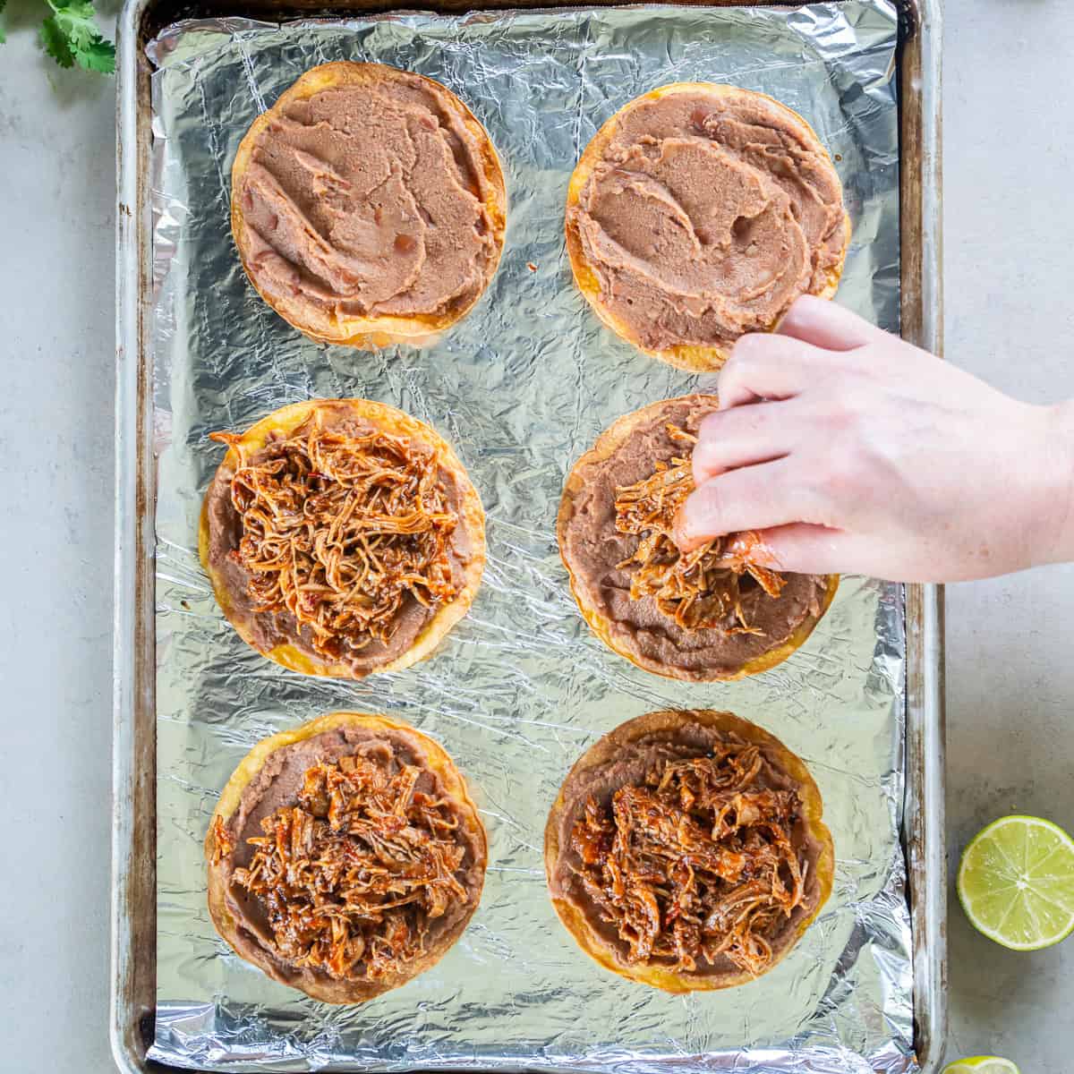 Chicken Tinga spooned over refried beans on crispy baked tostadas before adding the toppings.