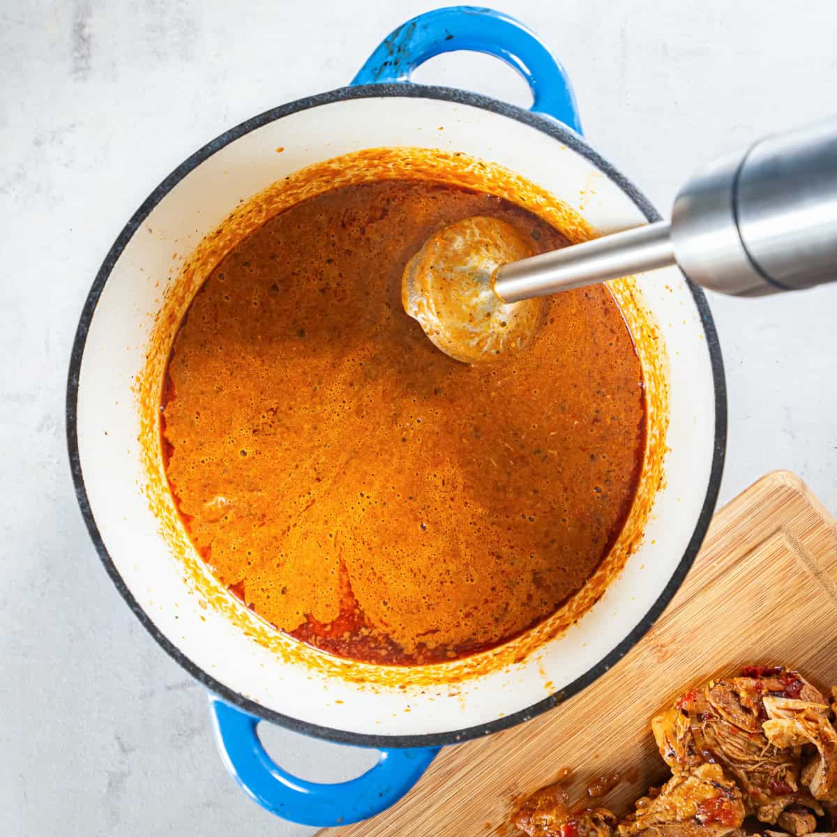 Blending the chipotle tomato sauce with an immersion blender until smooth.