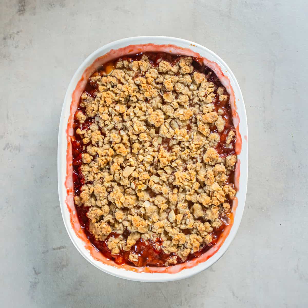 Freshly baked Peach Strawberry Crisp with a golden brown oat and almond topping.