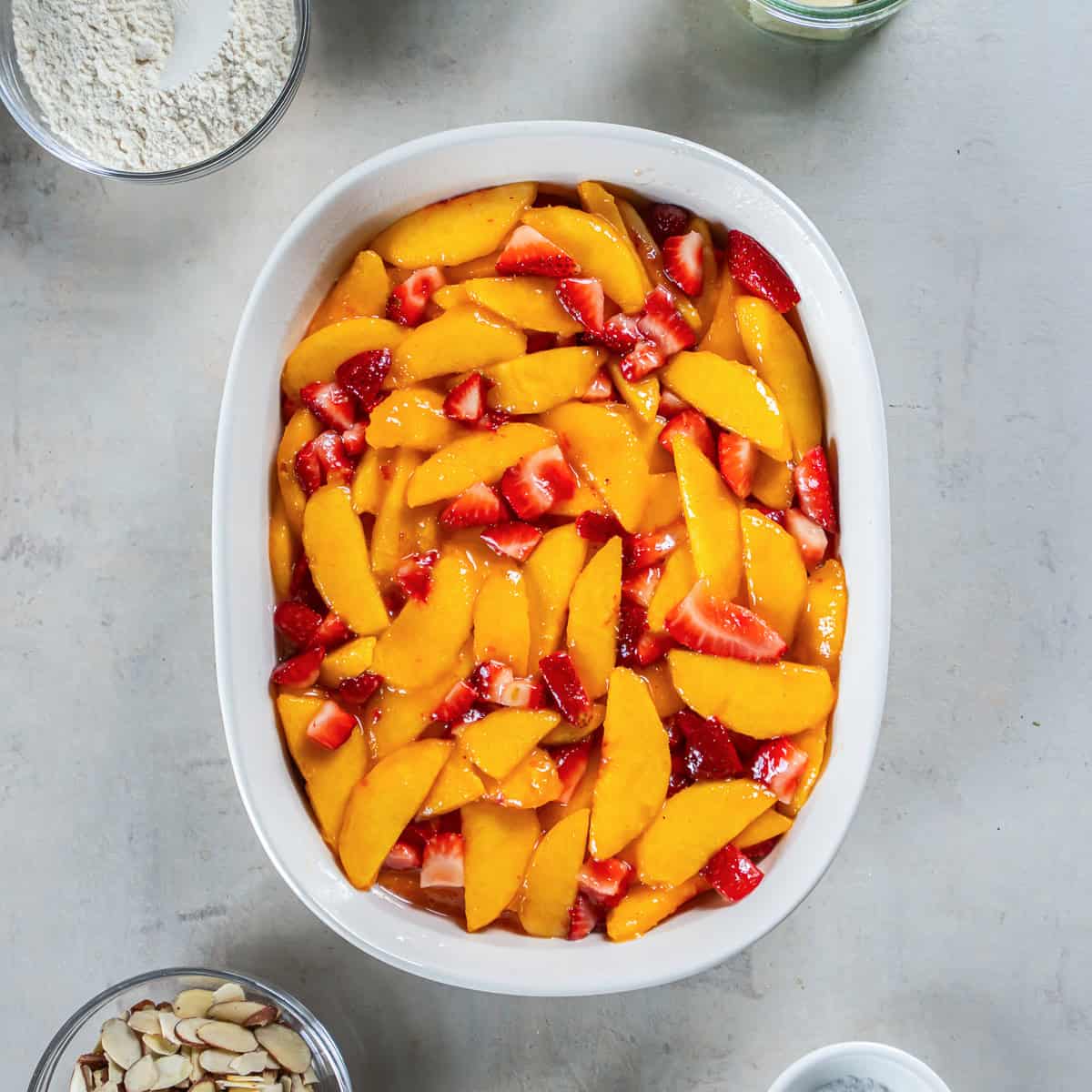 Peach and strawberry filling transferred to a baking dish.