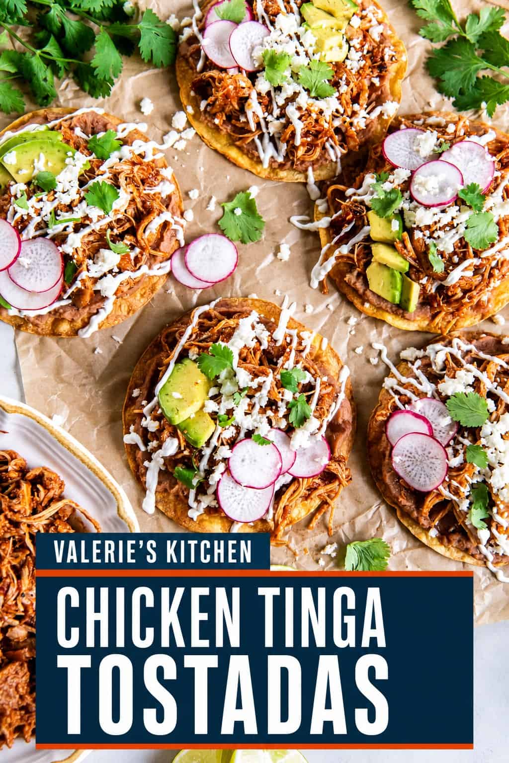 Chicken Tinga tostadas topped with refried beans, avocado, sliced radishes, Cotija cheese, cilantro, and Mexican crema, served with a bowl of Chicken Tinga and fresh lime wedges with bold text overlay.