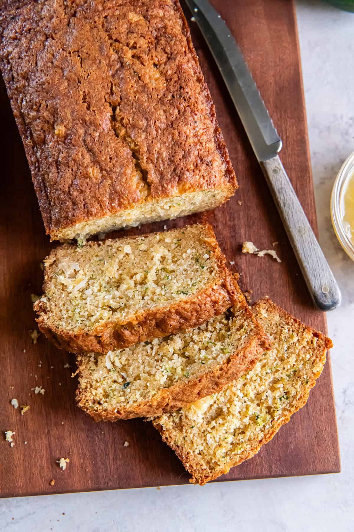 Loaf of Pineapple Zucchini Bread with several slices on a wooden cutting board.