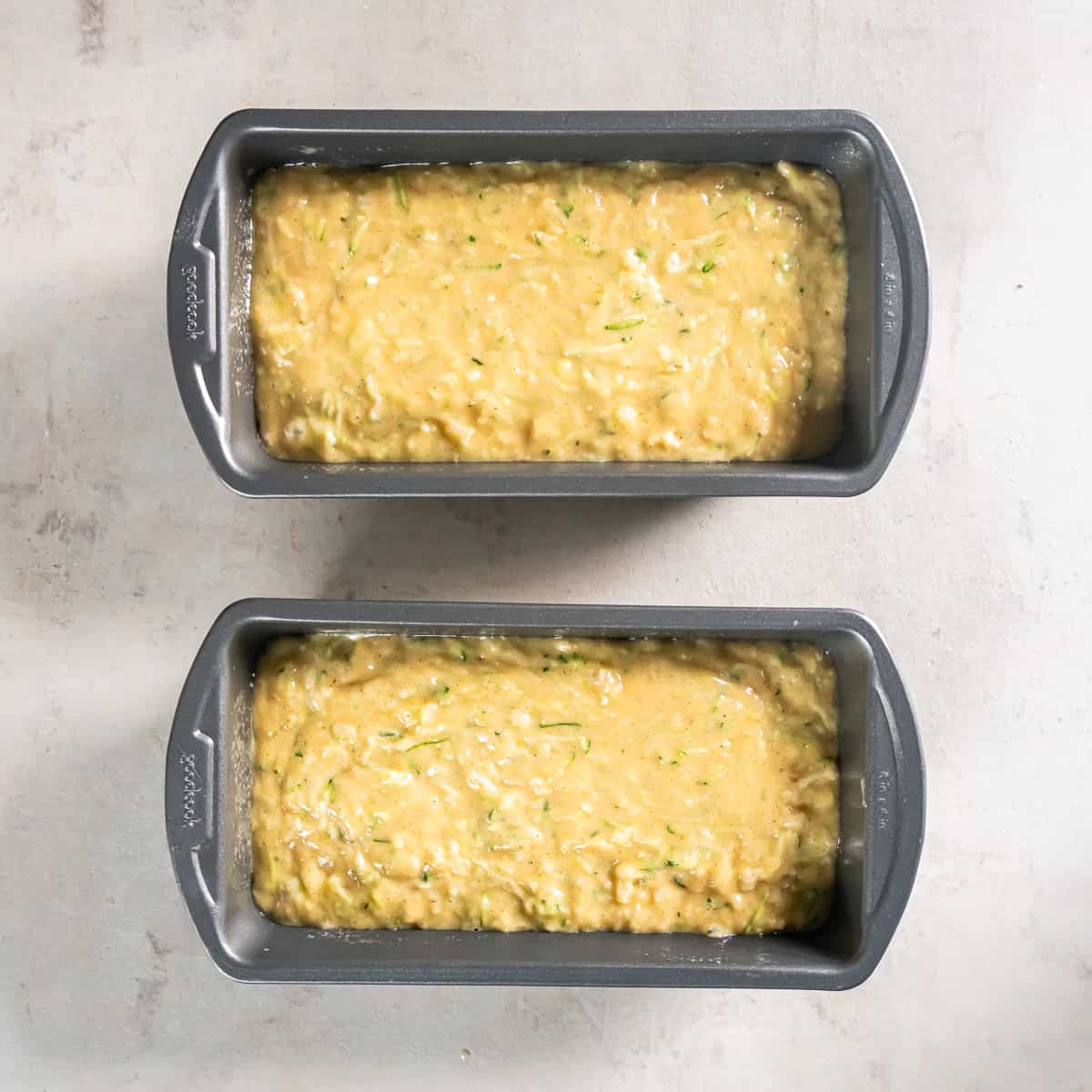 Pineapple Zucchini Bread batter divided evenly between two greased 8 x 4-inch loaf pans before baking.