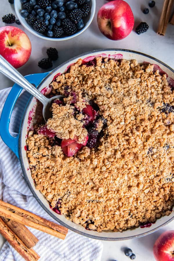 Apple Berry Crisp with a spoonful lifted from the baking dish, showing tender apples, berries, and a golden oat topping.