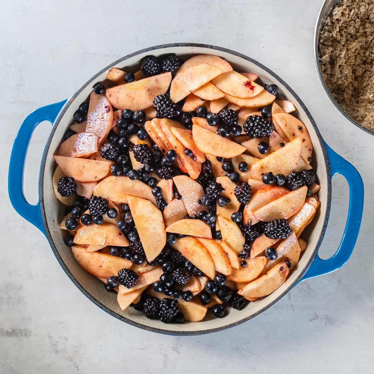 Sliced apples, blueberries, and blackberries tossed with sugar, cornstarch, cinnamon, ginger, and lemon juice for Apple Berry Crisp.