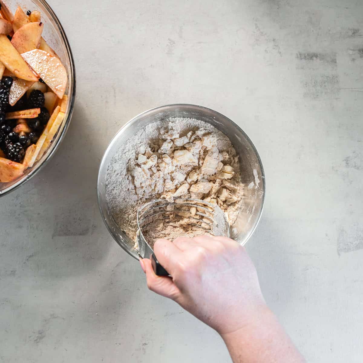 Using a pastry blender to cut cold butter into the oat and flour mixture for Apple Berry Crisp topping.