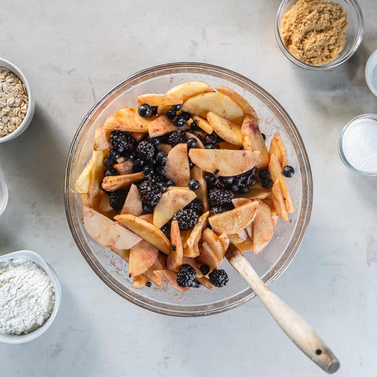 Sliced apples, blueberries, and blackberries tossed with sugar, cornstarch, cinnamon, ginger, and lemon juice for Apple Berry Crisp.