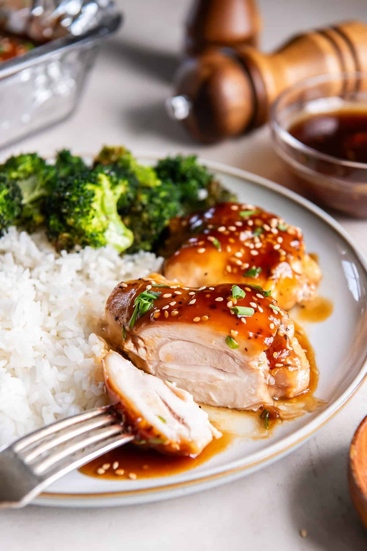 Close-up of Baked Teriyaki Chicken cut open to show the tender chicken inside, served with rice and broccoli.