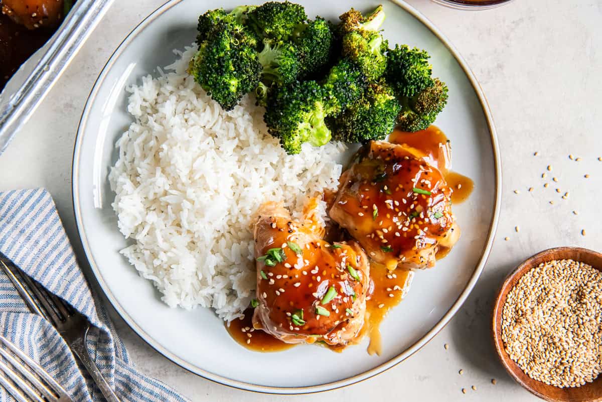 Baked Teriyaki Chicken served with white rice and broccoli, garnished with sesame seeds and green onions.