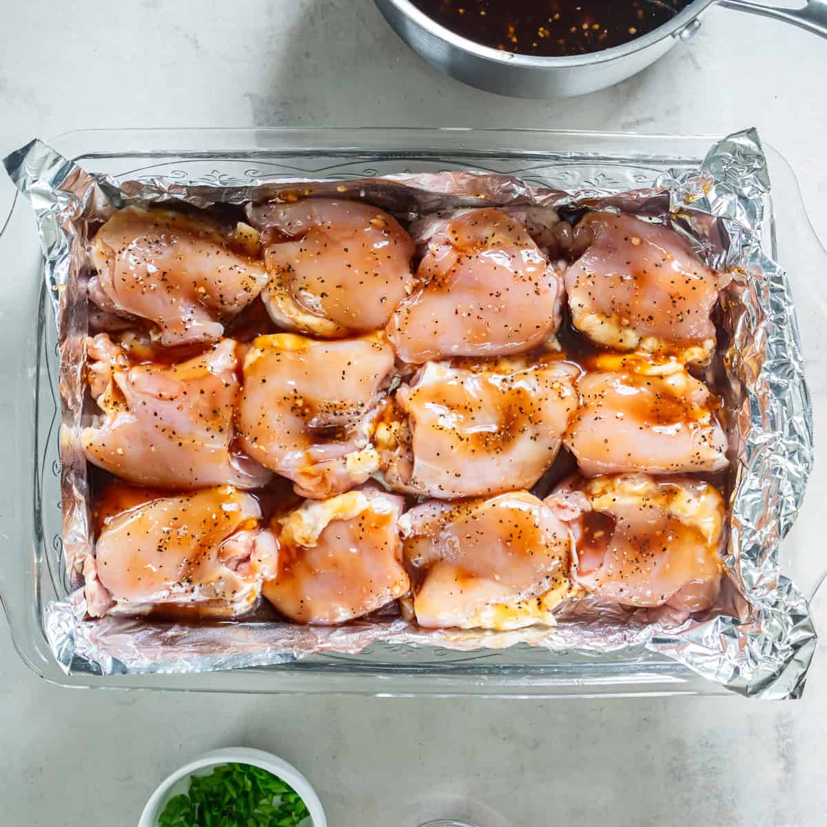 Teriyaki sauce spooned over seasoned chicken thighs before baking.