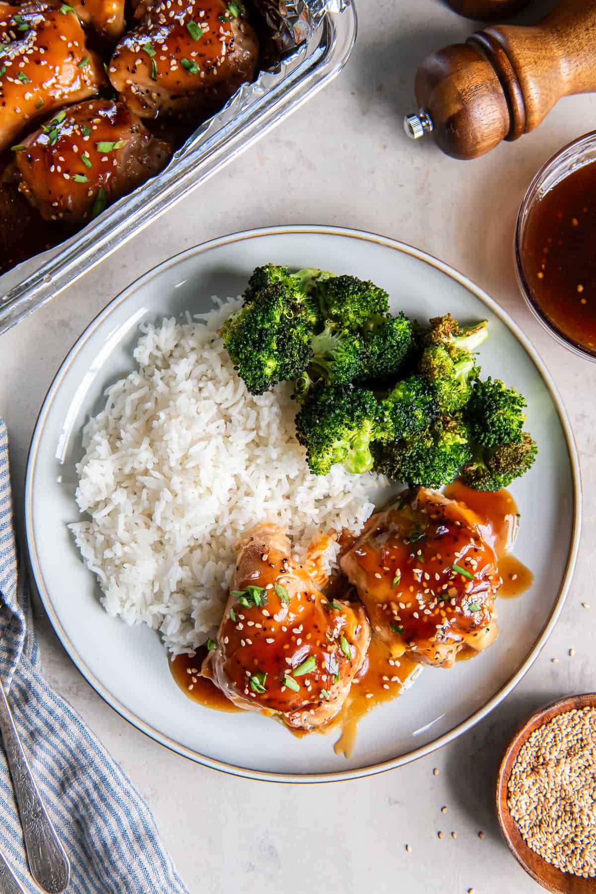 Baked Teriyaki Chicken served with white rice and broccoli, with the baking dish of glazed chicken alongside.