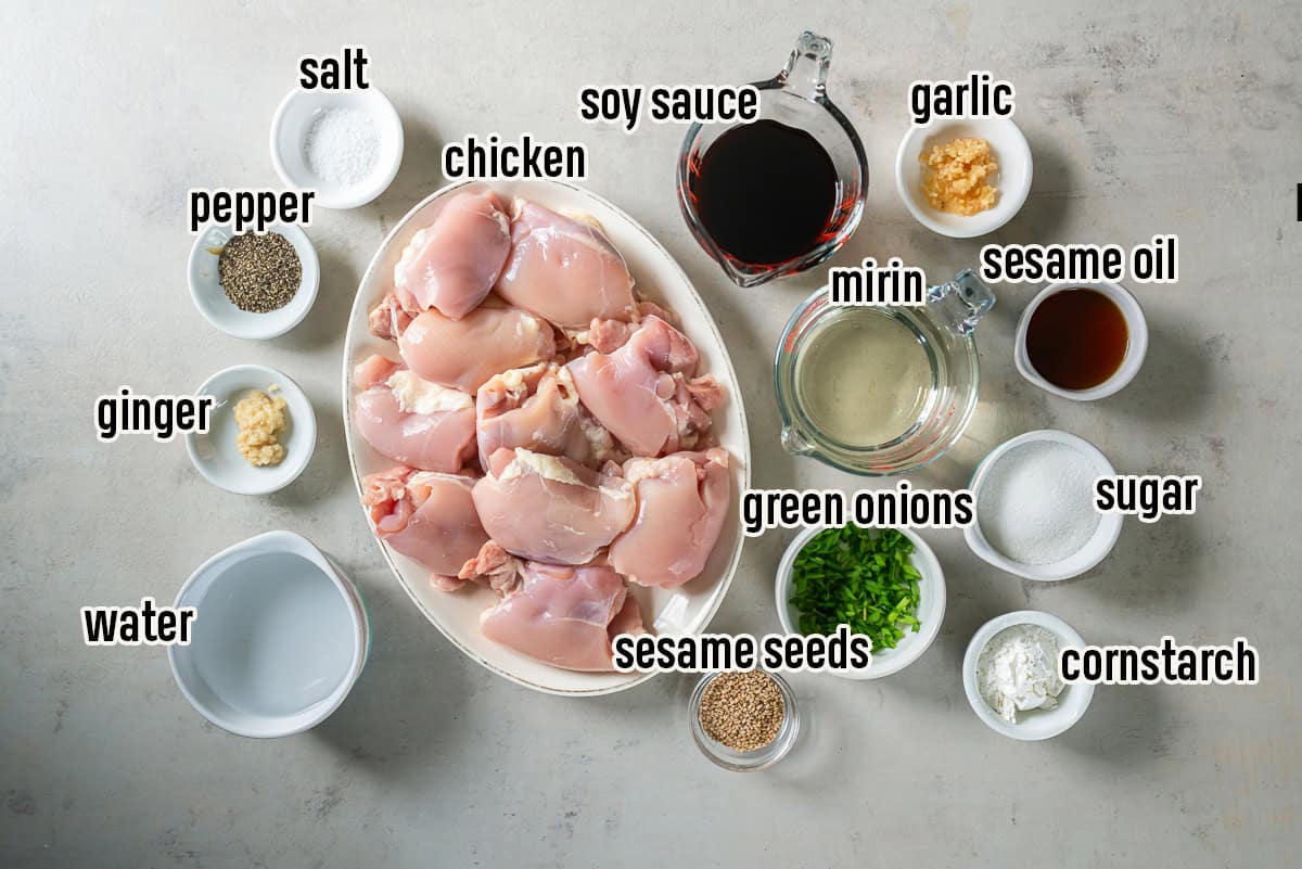 Ingredients for Baked Teriyaki Chicken, including chicken thighs, soy sauce, mirin, sesame oil, ginger, garlic, sugar, cornstarch, green onions, and sesame seeds.