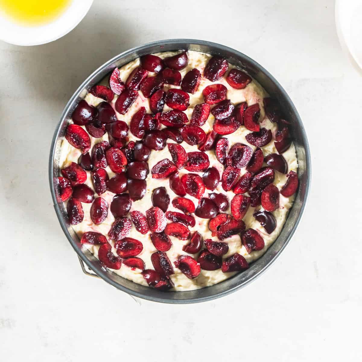 Scattering quartered fresh cherries evenly over the batter.