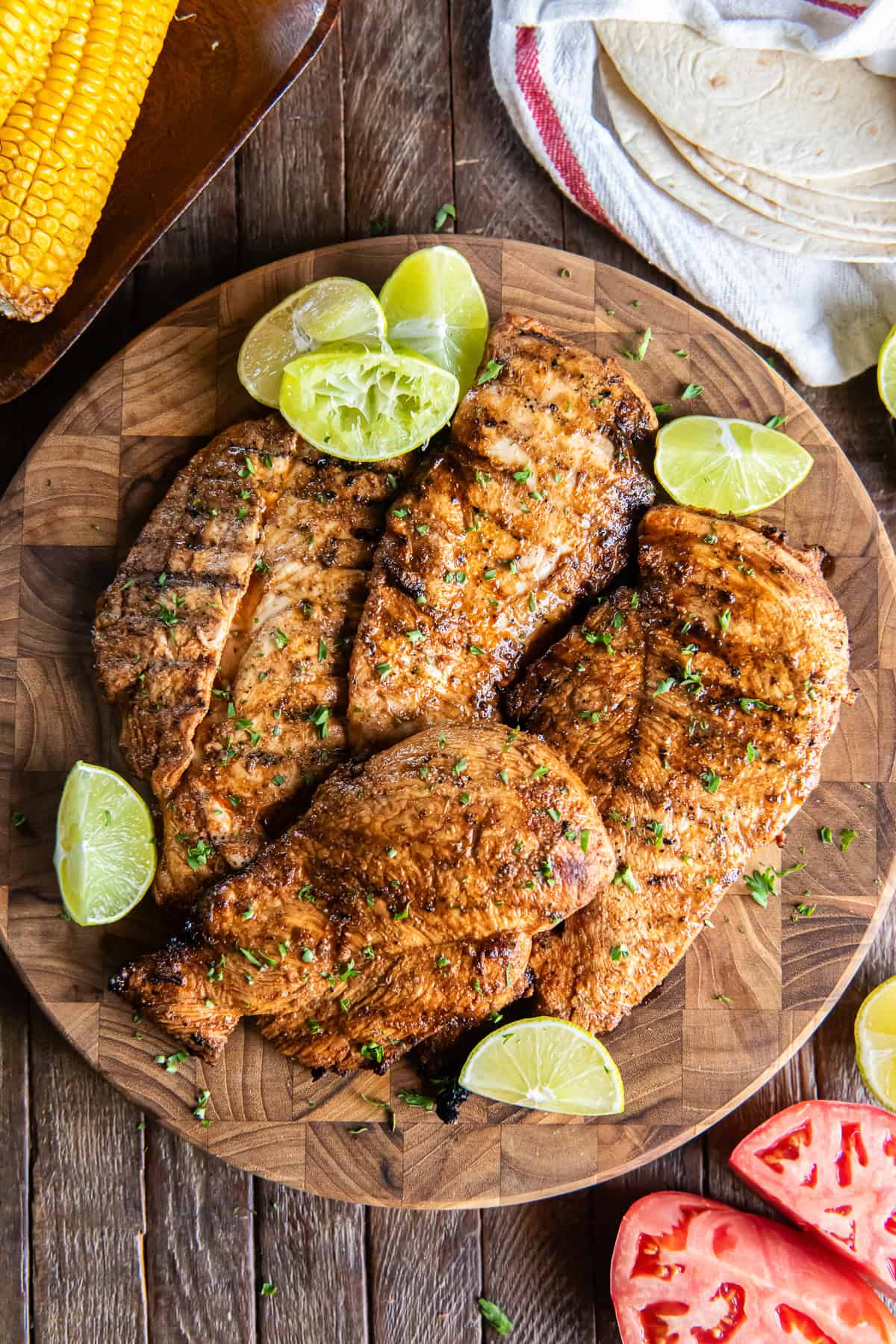 Grilled chili lime chicken breasts with browned edges and grill marks on a sheet pan.