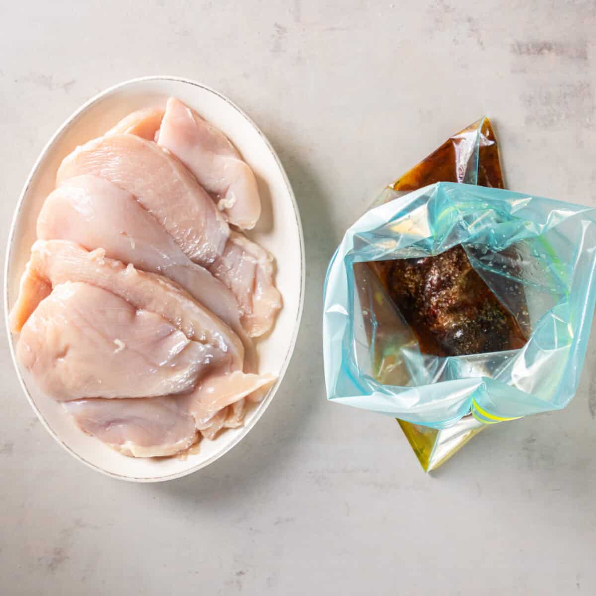 Raw chicken breasts beside a zip-top bag filled with chili lime marinade.