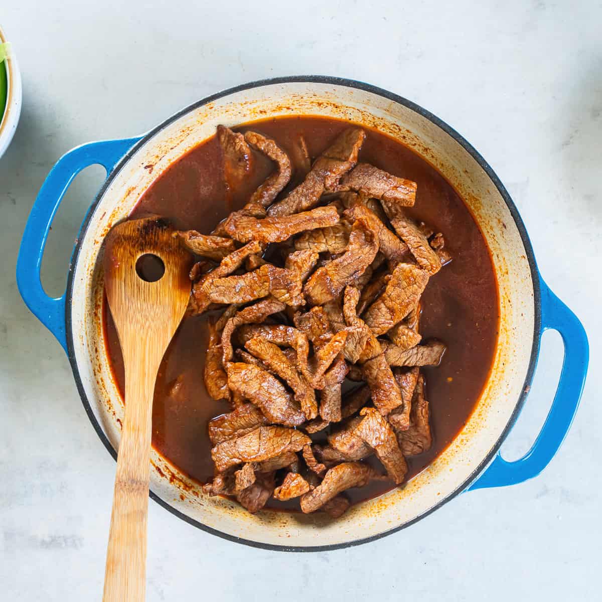 Browned beef returned to the skillet after adding the beef broth, soy sauce, sugar, and black pepper.