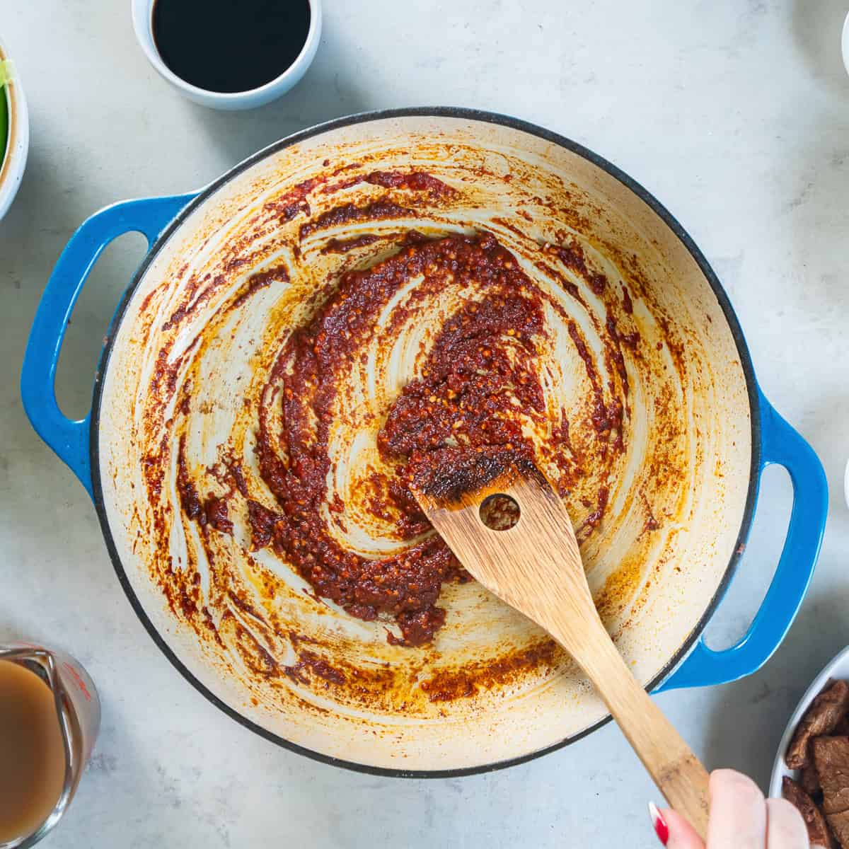 Garlic, ginger, and tomato paste cooking in the skillet until fragrant.