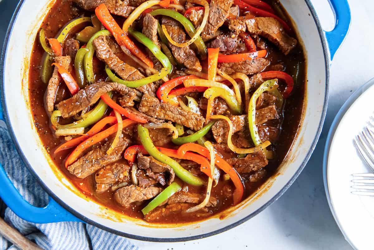 Classic pepper steak with tender beef strips, colorful bell peppers, and onion simmered in a rich brown sauce in a large skillet.
