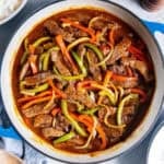 Easy Pepper Steak made with tender beef, bell peppers, and onion simmered in a flavorful brown sauce, served in a blue skillet with white rice on the side.