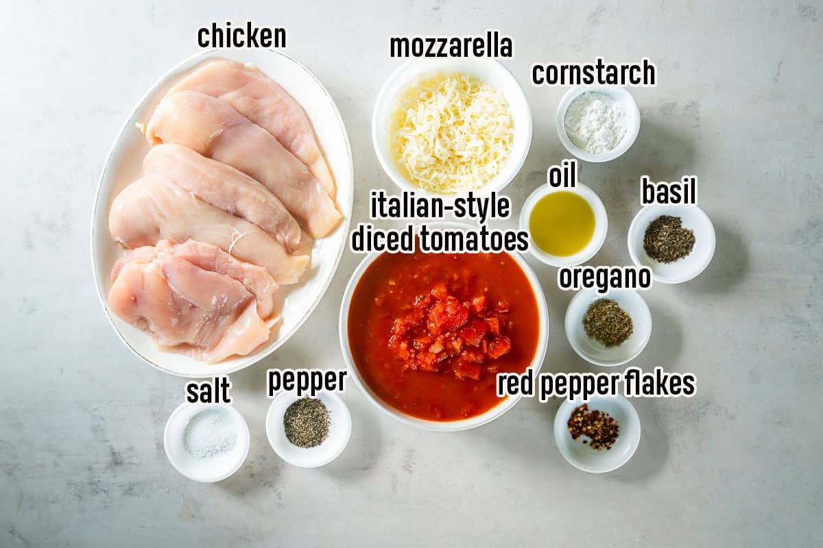 Ingredients for Easy Italian Chicken Bake, including boneless skinless chicken breasts, Italian-style diced tomatoes, shredded mozzarella, olive oil, cornstarch, dried basil, dried oregano, crushed red pepper flakes, salt, and black pepper.