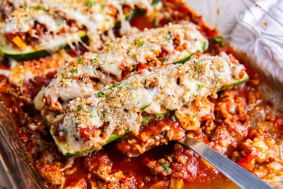 A spatula resting under an Italian Stuffed Zucchini Boat in a baking dish.