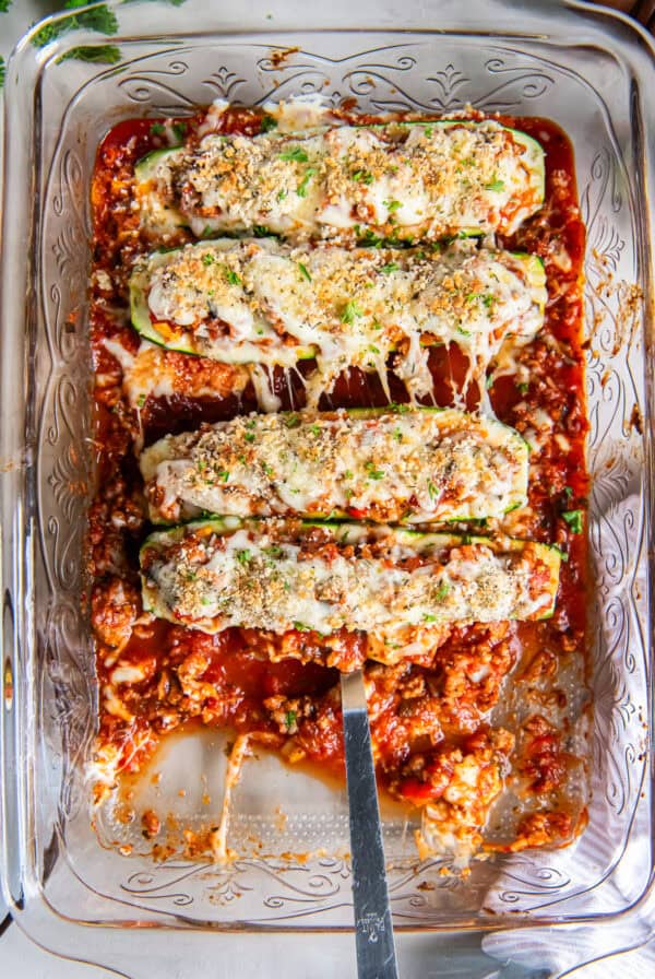 A spatula resting under an Italian Stuffed Zucchini Boat in a baking dish.