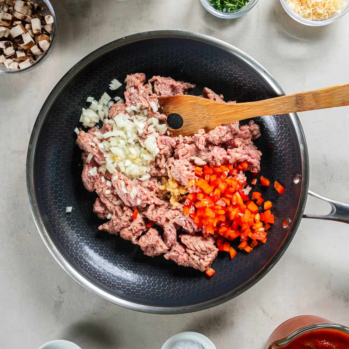 Ground turkey, onion, red bell pepper, and garlic cooking in a skillet for stuffed zucchini boats.