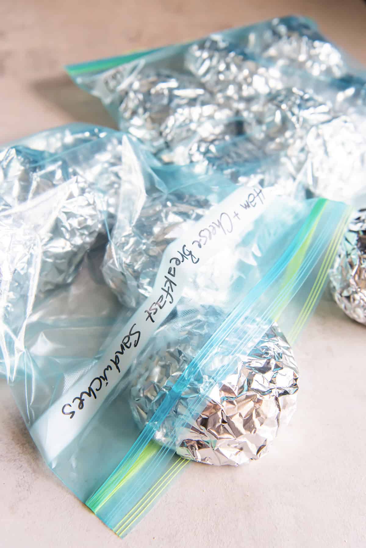 Foil-wrapped breakfast sandwiches stored in zip-top bags labeled “Ham + Cheese Breakfast Sandwiches.”