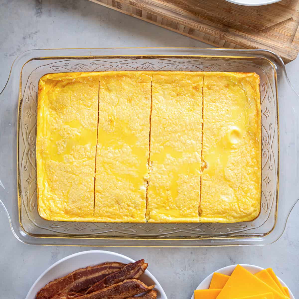 Baked egg mixture cut lengthwise into four equal sections in a glass baking dish.
