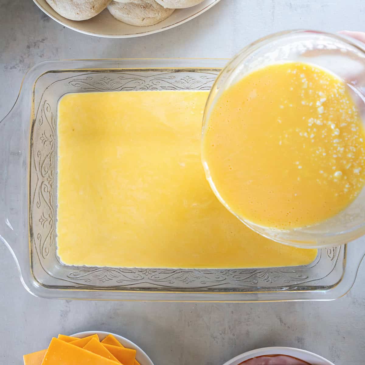 Eggs and cottage cheese being combined with a hand mixer in a glass mixing bowl.