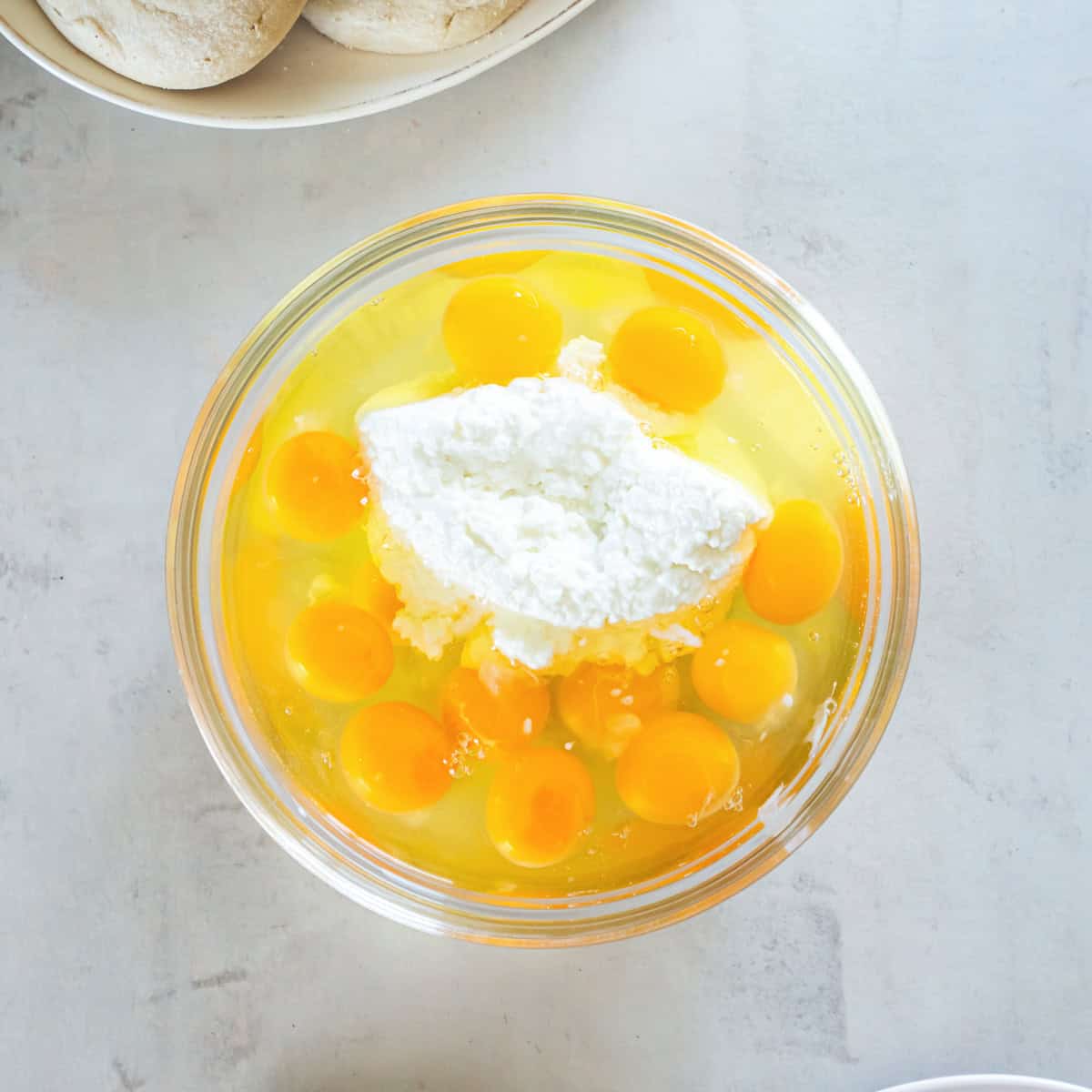 Eggs and cottage cheese in a mixing bowl before being combined for make-ahead breakfast sandwiches.