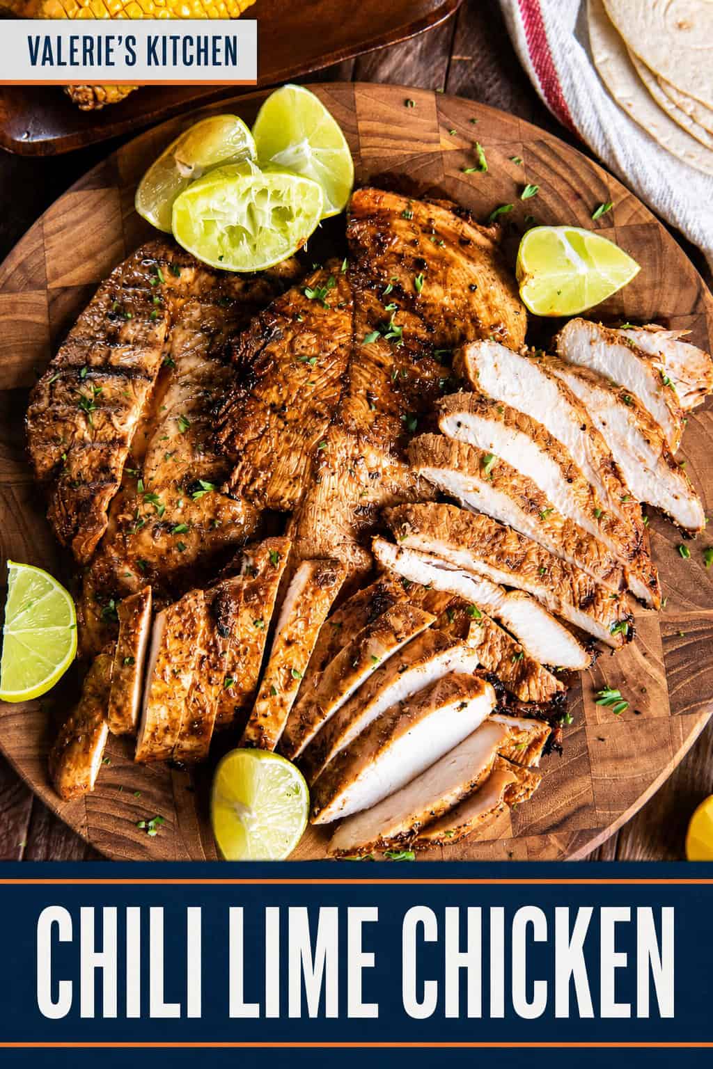 Grilled chili lime chicken breasts, some sliced, on a wooden serving board with lime wedges, tortillas, corn, guacamole, and tomatoes with bold title text overlay.