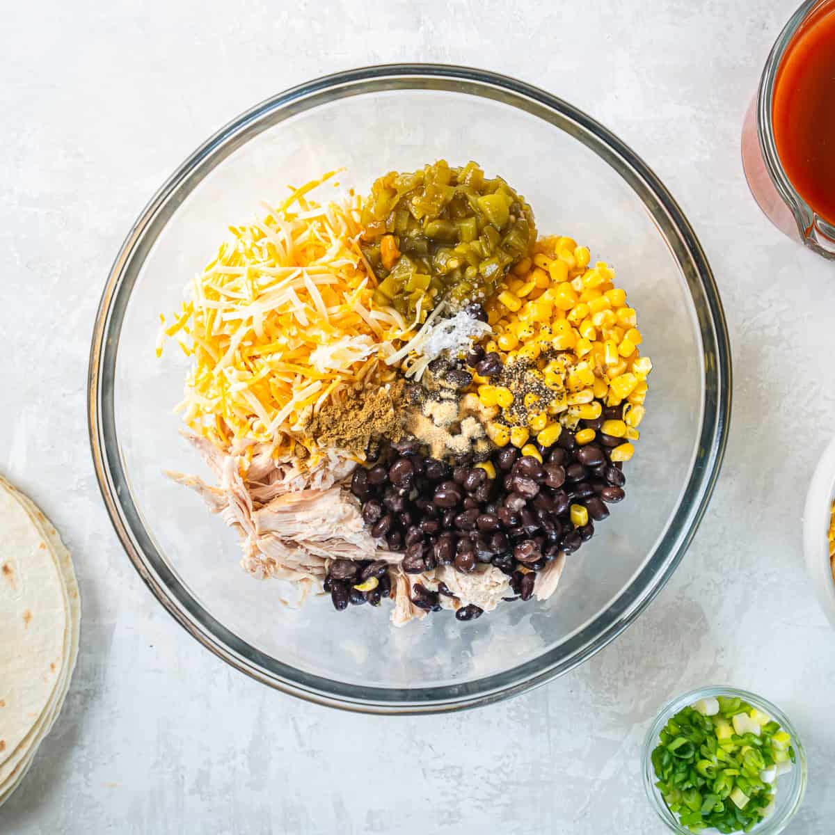 Rotisserie chicken, black beans, corn, green chiles, cheese, and seasonings combined in a bowl for Southwest Chicken Enchiladas.