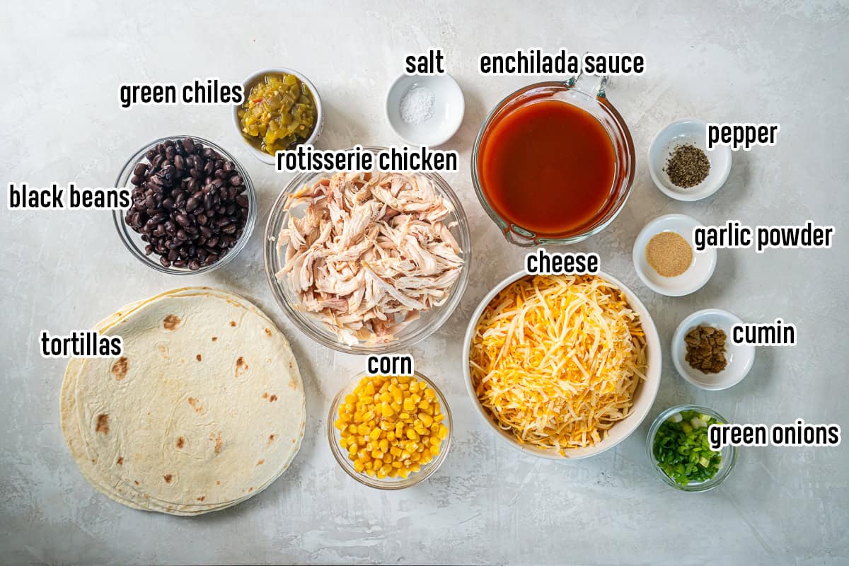 Ingredients for Easy Southwest Chicken Enchiladas, including rotisserie chicken, black beans, corn, green chiles, cheese, flour tortillas, red enchilada sauce, green onions, and seasonings.