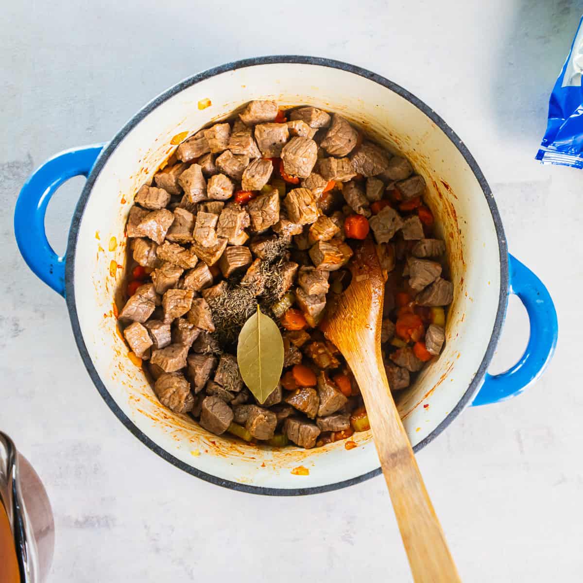 Browned beef returned to the Dutch oven with thyme and a bay leaf.