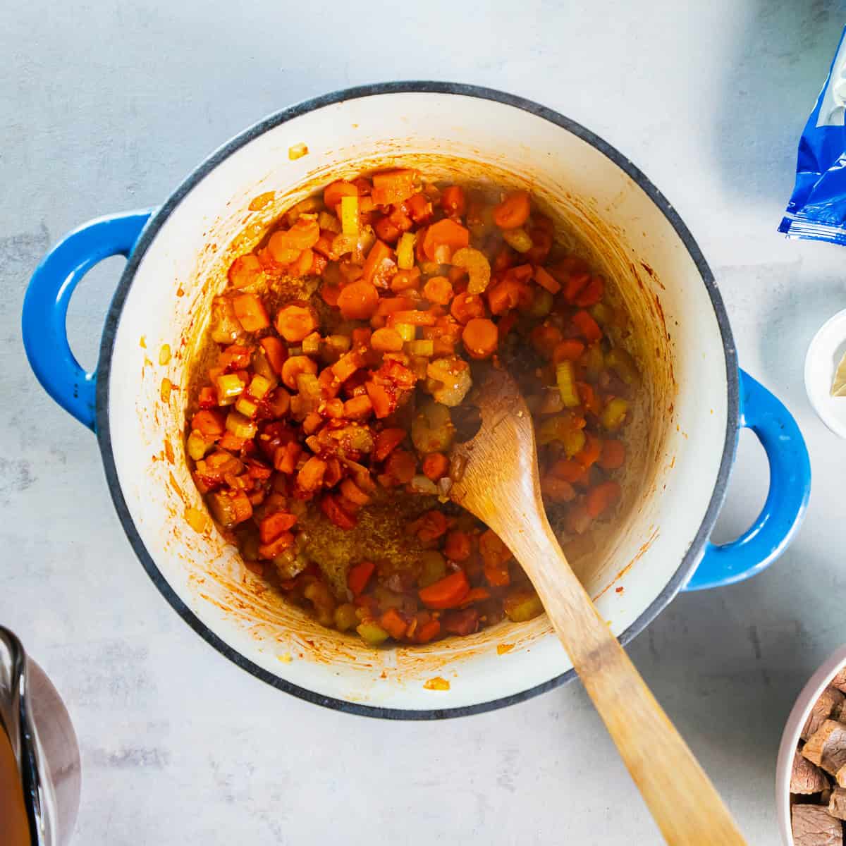 Carrots, celery, and onion cooking with tomato paste and garlic.