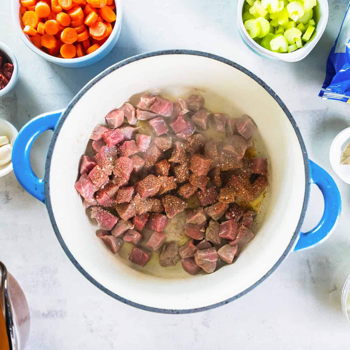 Beef cubes seasoned and browning in a Dutch oven.