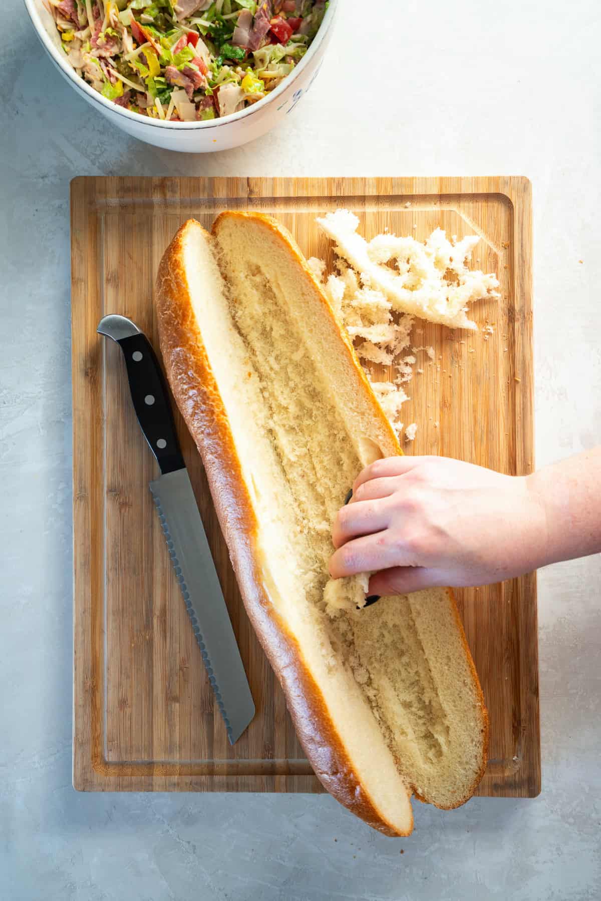 Soft French baguette sliced lengthwise and hollowed slightly to create space for the chopped Italian sandwich filling.