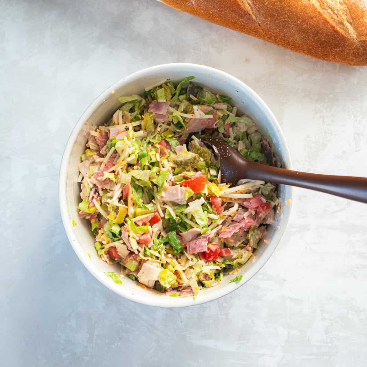 Chopped Italian sandwich filling tossed together with deli meats, cheese, lettuce, tomato, pickles, banana peppers, and creamy ranch dressing.