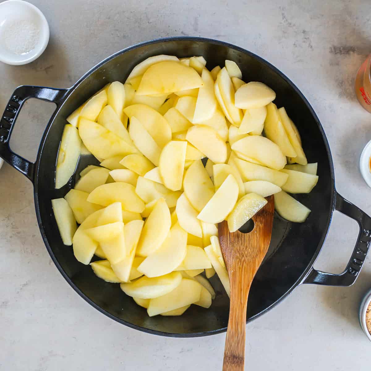 Peeled and sliced apples added to melted butter in a skillet.