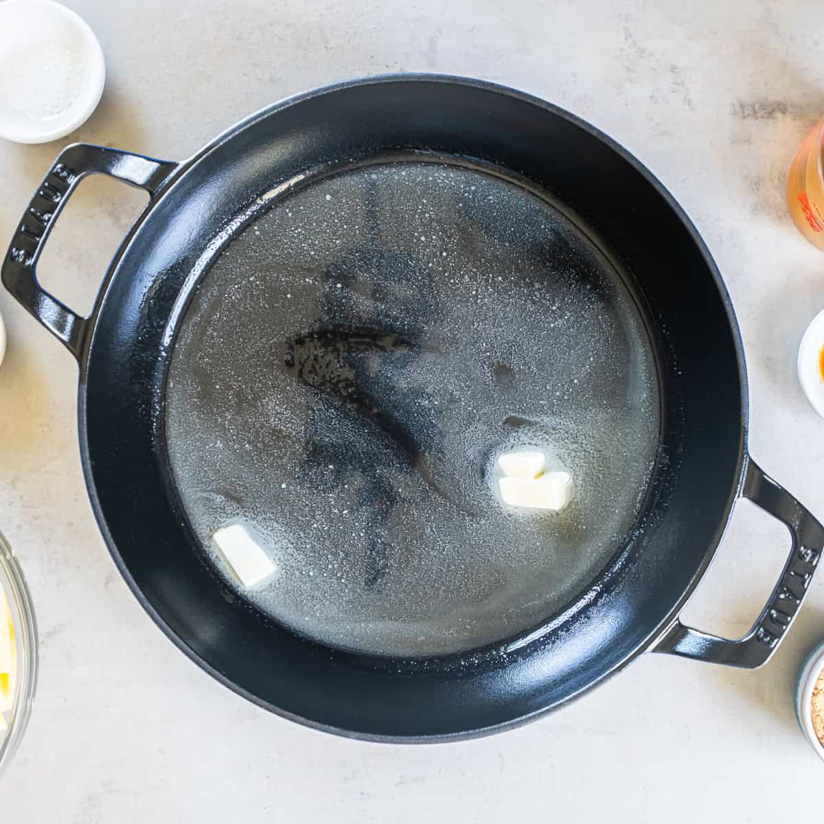 Butter melting in a large skillet for sautéed cinnamon apples.