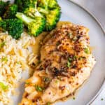 Maple mustard chicken breast with sliced garlic and sauce, served with rice and broccoli.