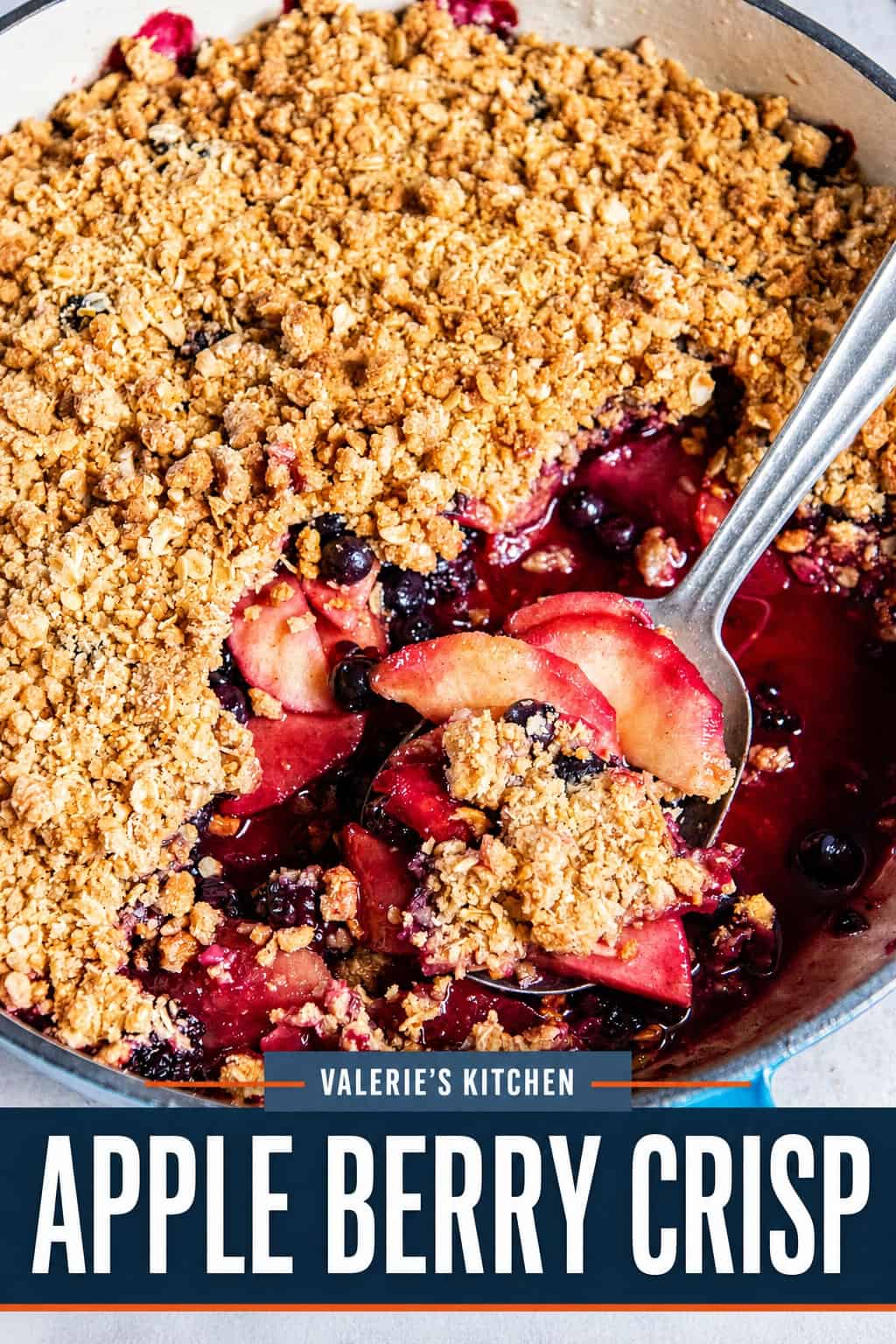 Apple Berry Crisp in a blue baking dish with a spoonful of tender apples and berries lifted through the golden oat topping with bold title text overlay.